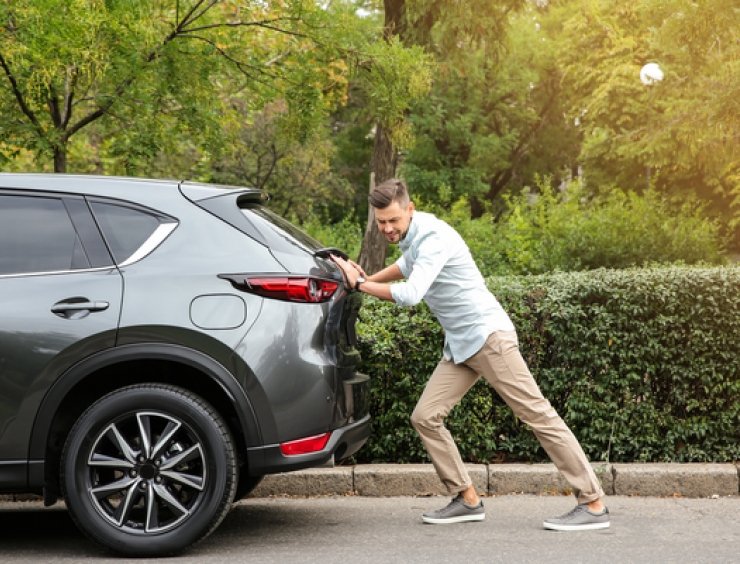 uomo spinge un'auto in panne