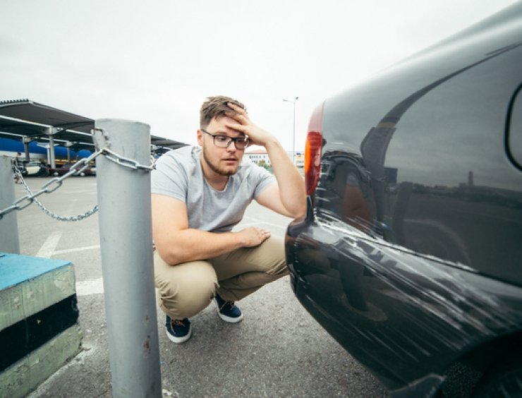 proprietario di un'auto guarda dei graffi sulla vettura con frustrazione